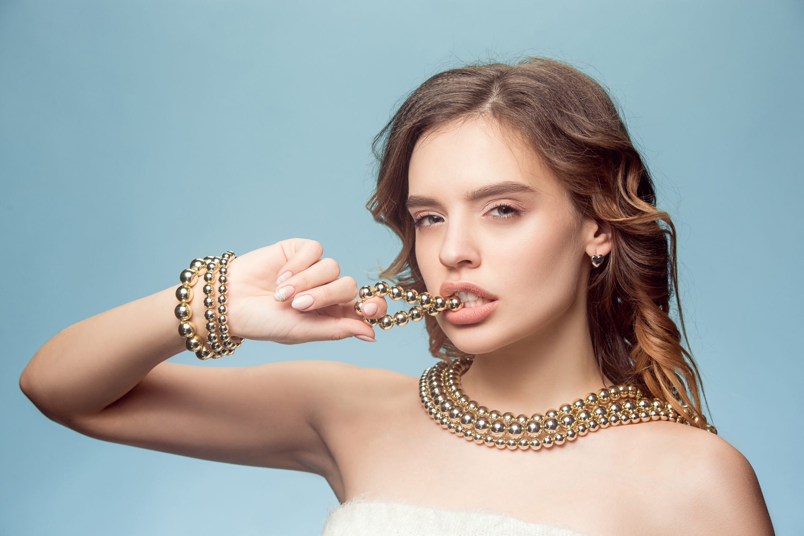 Beautiful young girl in studio with pearl jewelry - earrings, bracelet, necklace at blue studio.